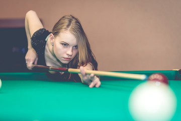 Fototapeta premium Beautiful young girl playing billiards, sexy woman in billiard room, pool