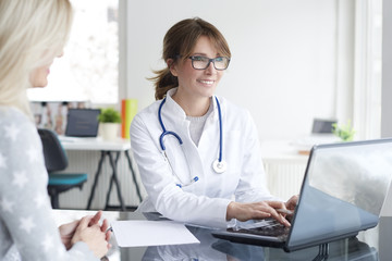 Doctor and her patient. Shot of a middle aged female doctor sitting in front of laptop and consulting with her patient.