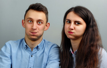 Funny young couple inflate his cheeks over gray background