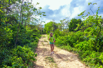 girl photographer on a dirt road among the green plants
