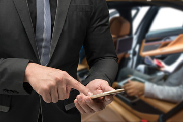 Fototapeta premium Chatbot future marketing and car sharing concept. Business man suit using smart phone with blur inside car background.