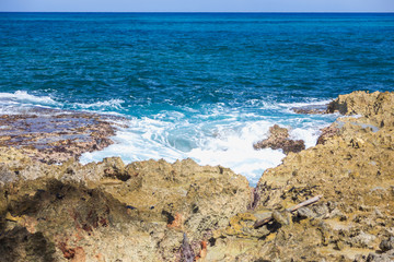 Foaming stormy sea and rocky shore in sunny weather