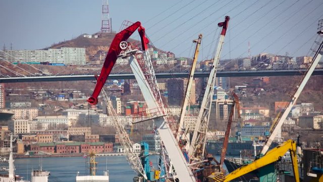 Vladivostok. Zolotoy Rog Bay Bridge. Crane Working on Ship Going Up. Boats on the Water. City Buildings on Shore. Hills on Background. Autumn