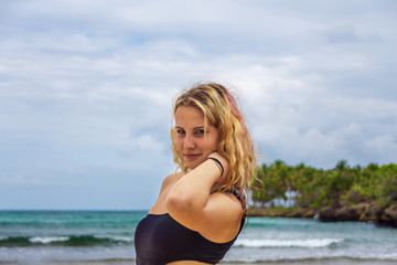 Fototapeta na wymiar Young happy girl in black bikini near the wild shore. Samana, Dominican Republic