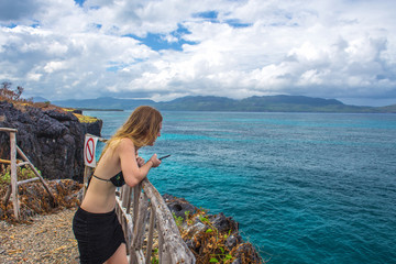 Fototapeta na wymiar Girl watching the blue sea from the high cliff. Samana, Dominican Republic