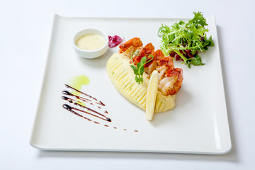 Fried shrimps with mashed potatoes with sauce on a white plate garnished with fresh lettuce. Stir fry shrimp.