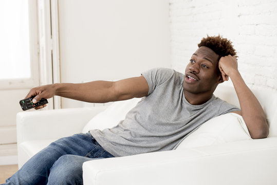 attractive black african american man sitting at home sofa couch watching television