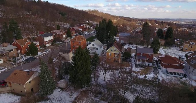 A slowly rising aerial winter view of a typical Western Pennsylvania residential neighborhood.  	
