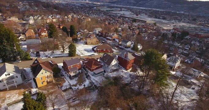 A slowly moving reverse aerial winter view of a typical Western Pennsylvania residential neighborhood and valley community.	 	