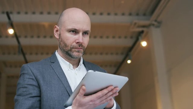 Businessman Using a Tablet and Raising His Eyes