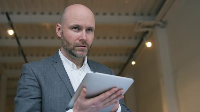 Middle-Aged Businessman Focused on Work with Tablet