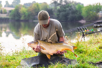 Happy angler with carp fishing trophy