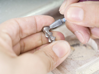 Dental technician is working with articulator in metal structure of a dental crown or bridge in dental laboratory