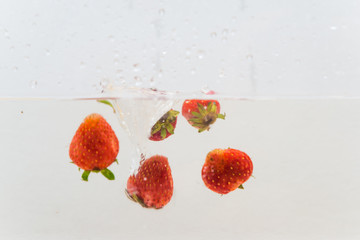 Group of strawberry splashing in clear water