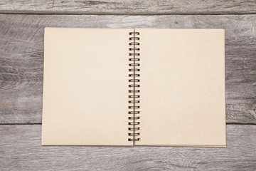 A blank recycled paper scrapbook sits on a rustic wooden background.