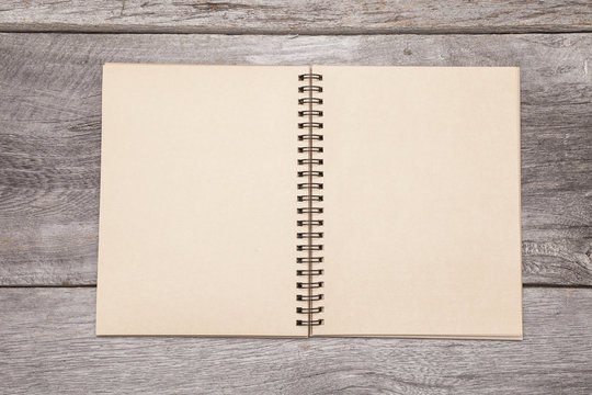 A blank recycled paper scrapbook sits on a rustic wooden background.