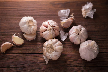 Garlic and garlic press on rustic wooden board.
