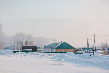 Rural house in the winter. From a pipe of the house there is a smoke.