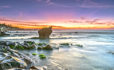 Dawn on ancient rocks moss covered with colorful sky welcome beautiful new day on the bay