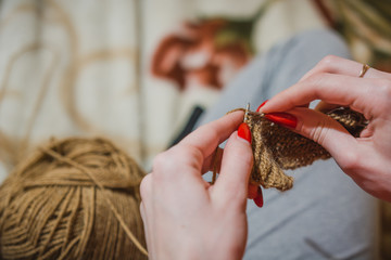 The girl knits spokes. The girl knits a sweater spokes from the shestyankh of threads.