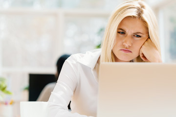 Unhappy young woman sitting at her desk