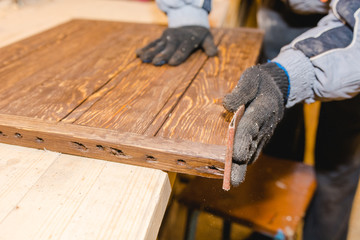 The man grinds wood. The joiner processes wooden boards. Joiner's works of the house.