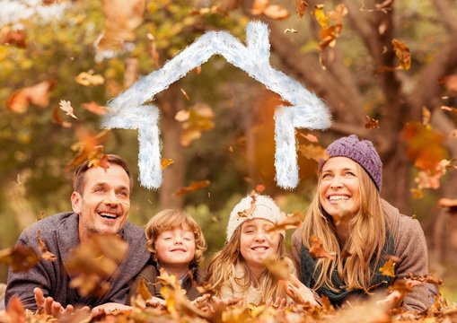 Family overlaid with house shape lying on dry leaves in park 