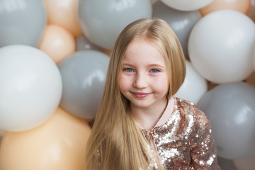 Naklejka premium Portrait of pretty little blonde girl on a balloons background