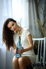 Blue bottle with dried flowers in the hands of a girl close up