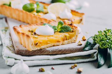 Tart with lime and lemon curd, nut pistachios and meringue. Citrus cake. Horizontal image with copy space