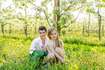Fototapeta premium A boy and a girl are resting in a blooming garden in the spring