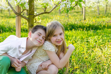  A boy and a girl are resting in a blooming garden in the spring