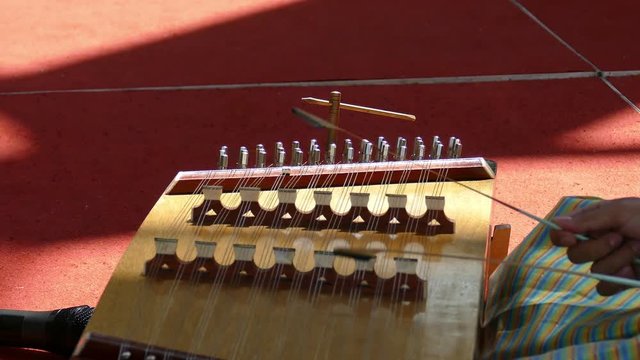 A young asian woman in thailand traditional cloth plays a song on a hammered dulcimer,Thai wooden dulcimer musical instrument
