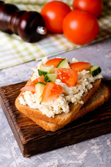 Breakfast with scrambled eggs and fresh vegetables on bread