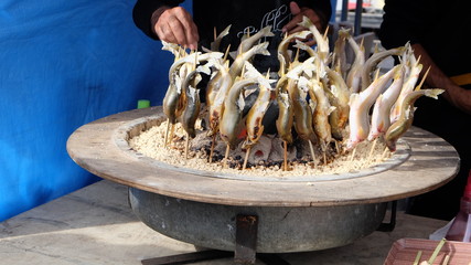 Japanese yakizakana or salted grilled fish on skewers in circle surrounding hot coals