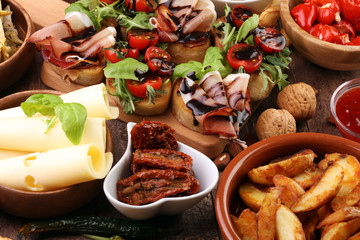 Fototapeta premium Italian antipasti wine snacks set. Cheese variety, Mediterranean olives, pickles, Prosciutto di Parma, tomatoes, artichokes and wine in glasses