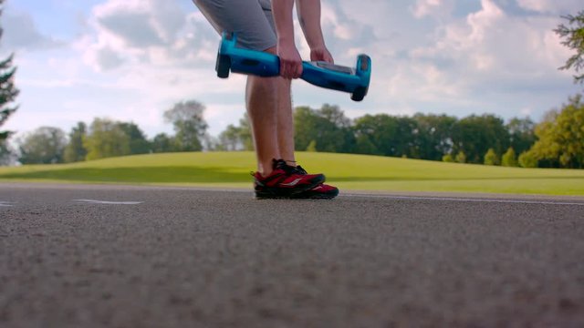 Young man put gyro scooter on asphalt road. Man preparing to ride on gyroscooter in city park.