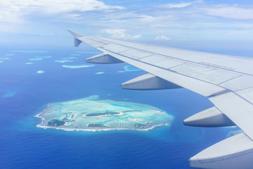 Obraz premium Scenery from airplane 's window seeing wing of airplane , white clouds , blue sky and Maldives islands