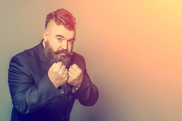 Adult bearded man in a suit showing fists  in the sunlight