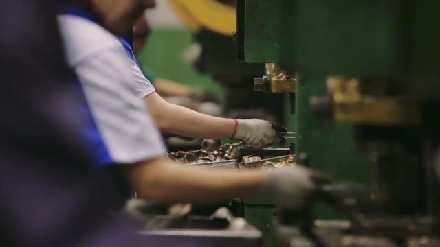 Workers manually assemble components at a Factory. Equipment in the plant. Dangerous production. Close-up