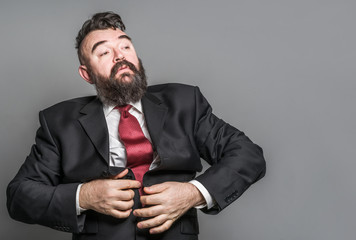 Adult bearded man in a suit and red tie on a gray background
