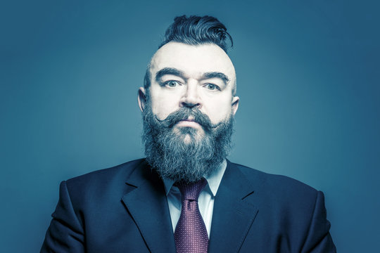 Adult bearded man in a suit with mohawk hairstyle on a blue background. Toned