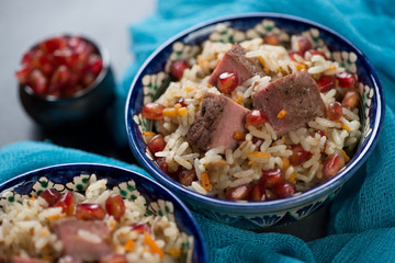 Close-up of pilaf with beef meat and pomegranate seeds, selective focus