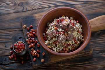 Ceramic bowl with georgian style pilaf in a rustic wooden setting, high angle view, studio shot
