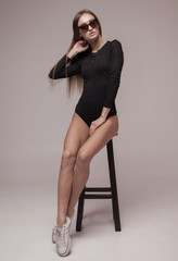 Naklejka premium Sexy brunette woman posing in erotic lingerie, looking at camera. Perfect slim body