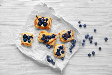 Sweet tasty pastries on craft paper against wooden background, top view
