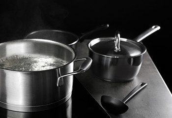 Metal pan with steam on dark background