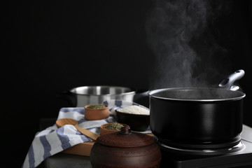 Metal pan with steam on dark background
