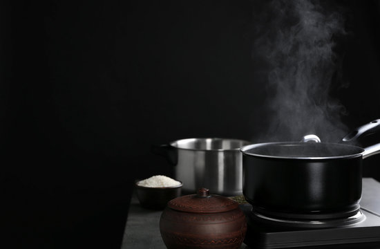 Metal pan with steam on dark background