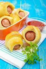 Freshly baked small buns in a ceramic bowl. Sausage in the dough. Vertical view